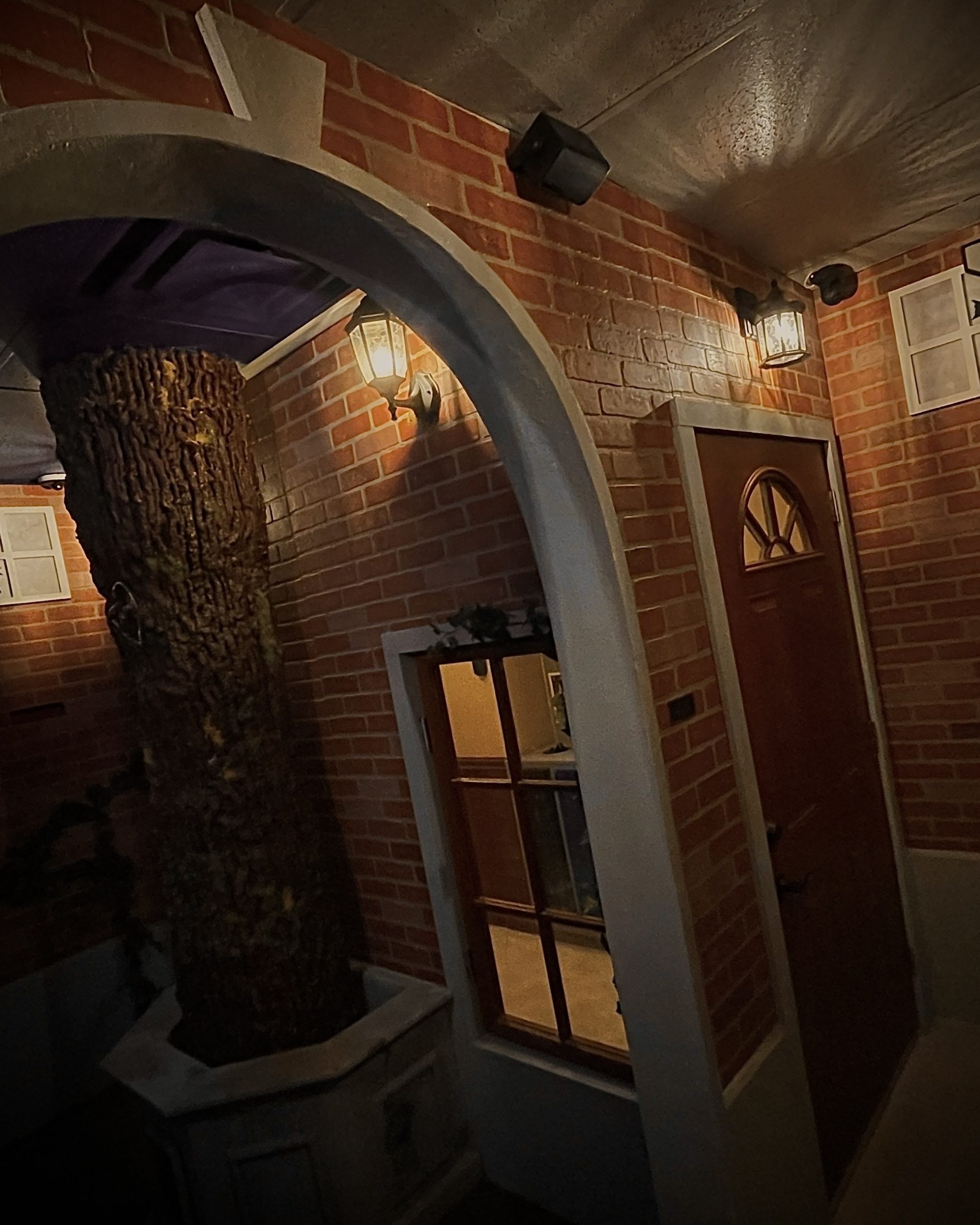 Escape room set with a brick archway, wall lanterns and a wooden front door